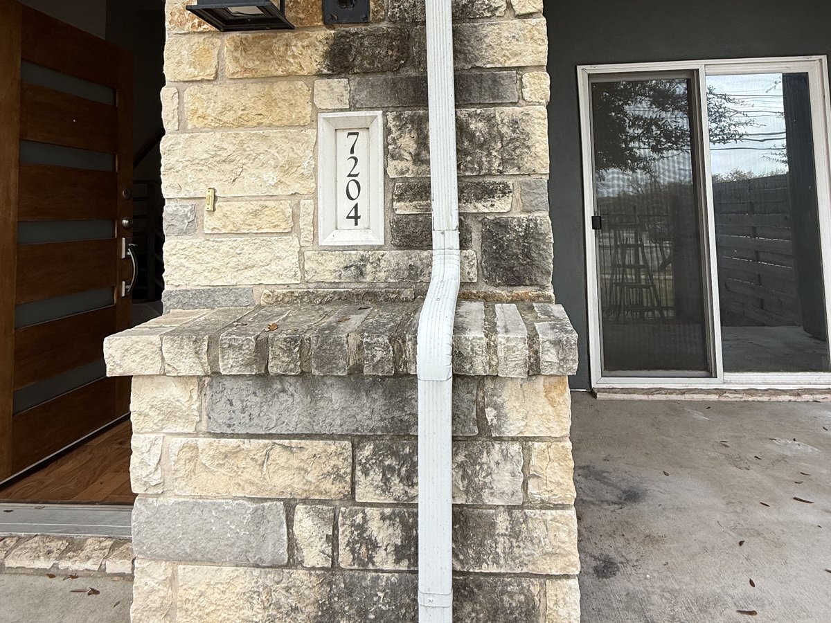 Before soft washing — dirty stone exterior with algae and grime buildup